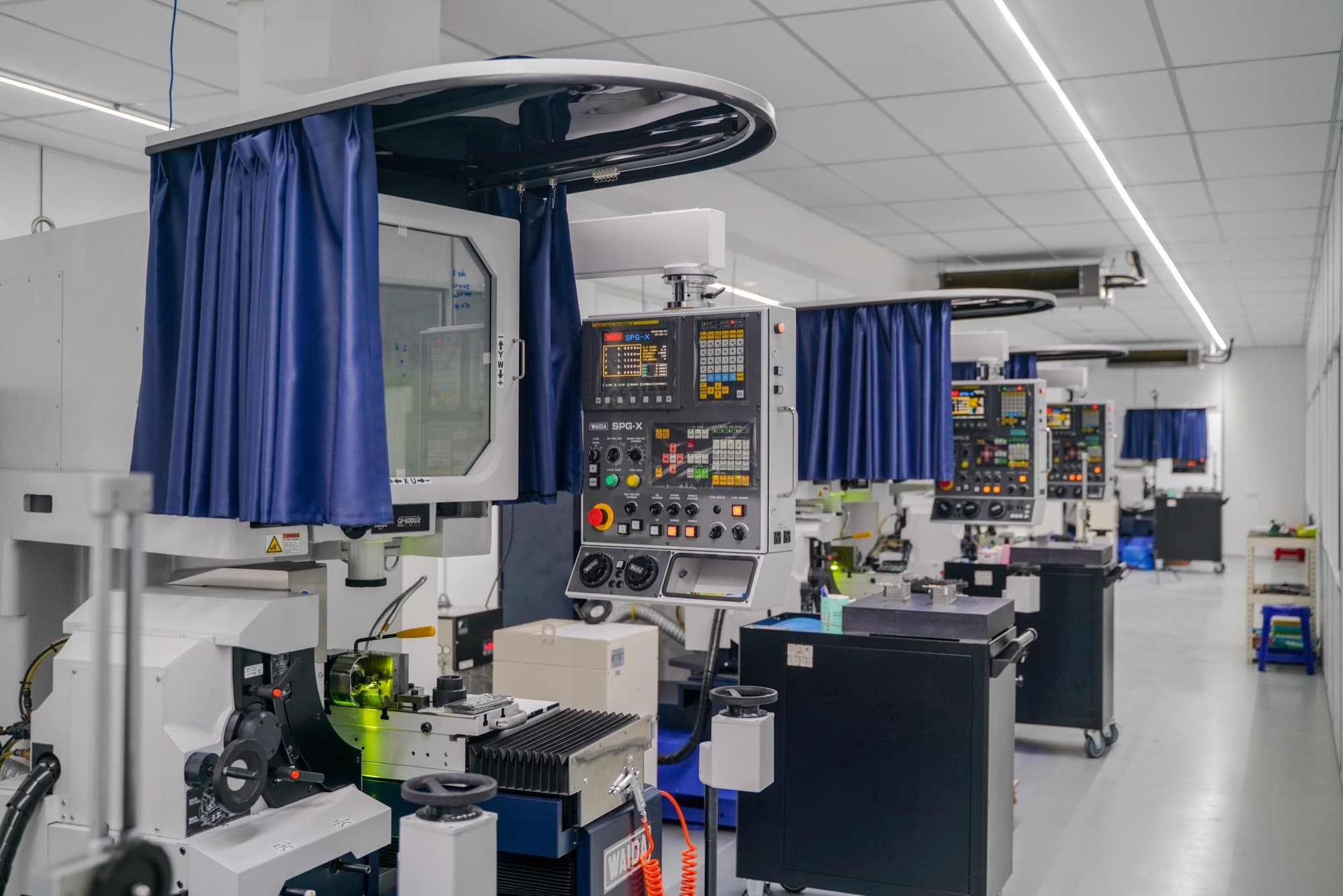 A row of WAIDA SPG-X CNC profile grinding machines on the shop floor of K-TOOL Engineering's profile grinding department in Penang, Malaysia
