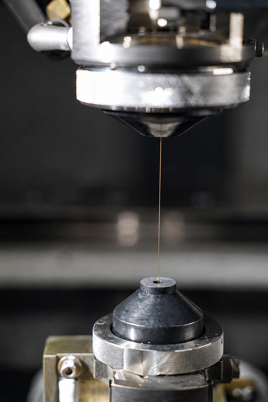 Brass EDM wire threaded through the upper and lower guides of a wire EDM machine at K-TOOL Engineering in Penang, Malaysia